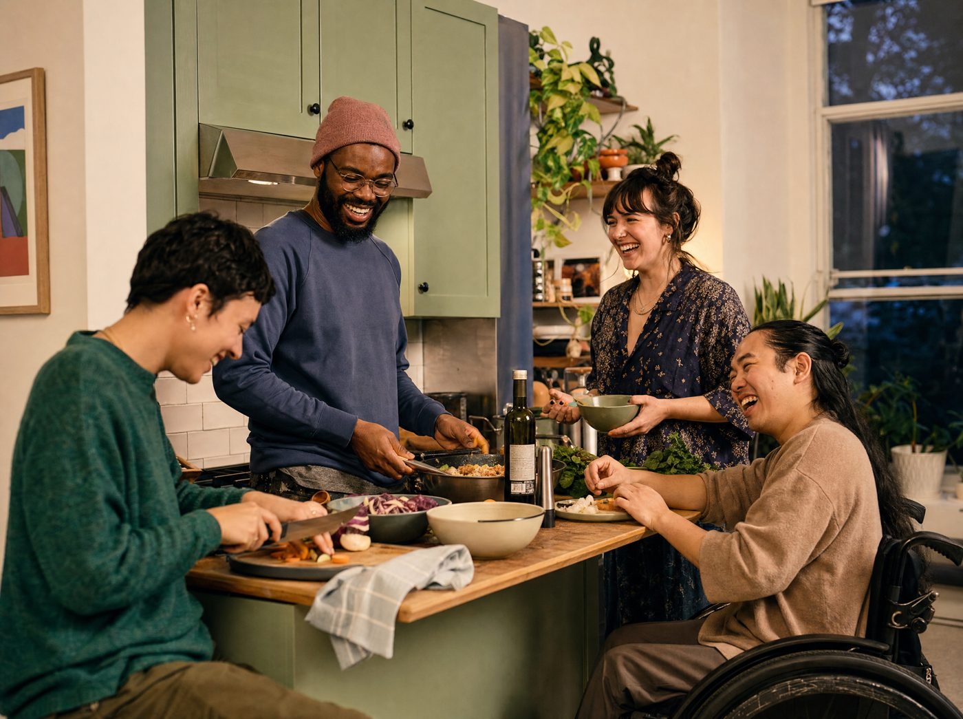 Bewohner*innen einer Wohngemeinschaft kochen gemeinsam und lachen